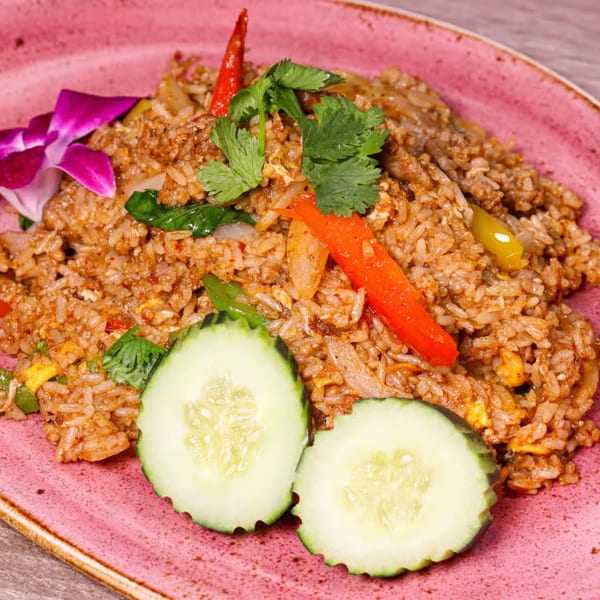 NUA Thai fried rice with red chili, cilantro, and cucumber slices on a pink plate.