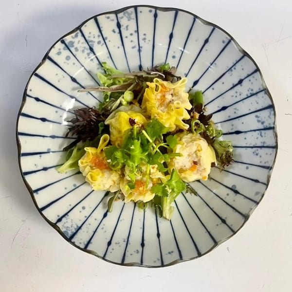 NUA Thai's steamed dumplings with fresh herbs and greens in a decorative bowl.